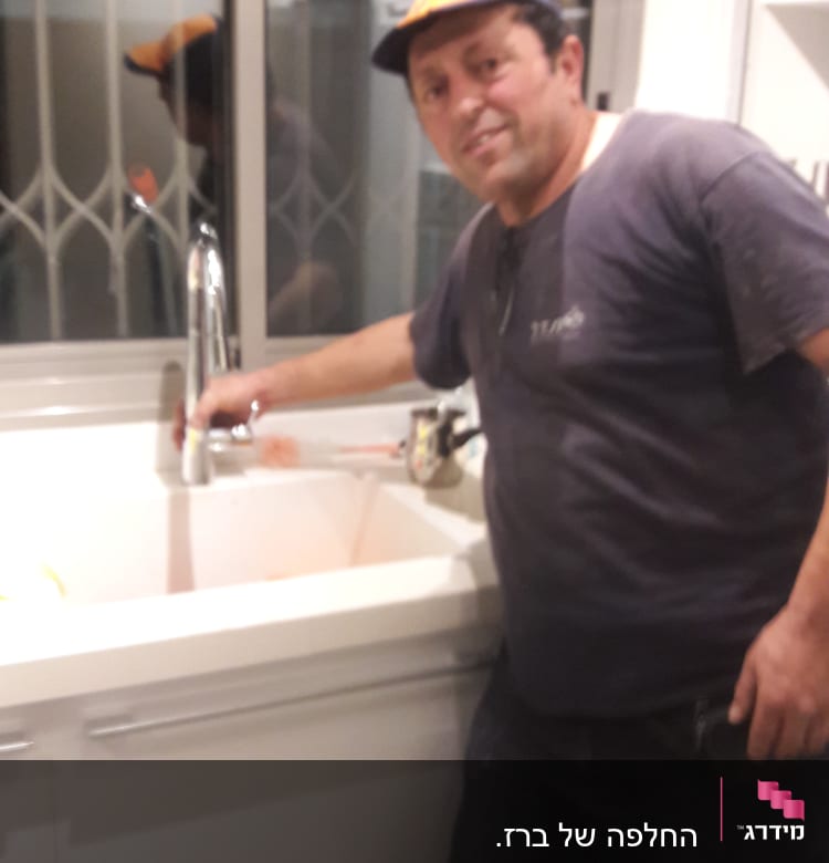 אדם ליד כיור מטבח עם ברז כרום
